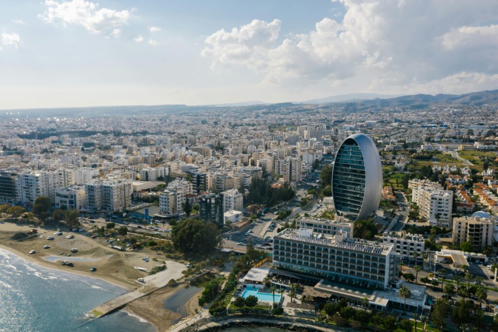 A breathtaking aerial view of Limassol's modern architecture by the seaside, featuring a unique oval-shaped building.